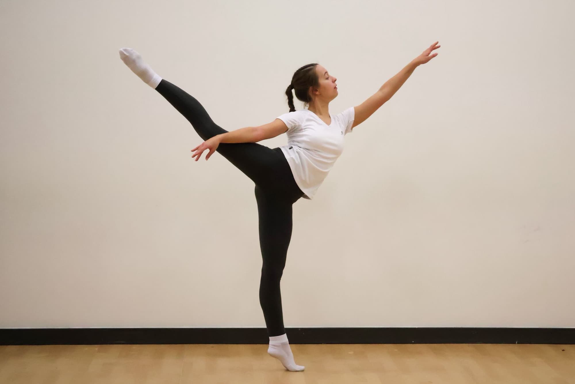 A senior dancer holding an arabesque in the studio